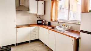 A compact kitchen with white cabinets, a microwave, a sink, and a window with curtains. - Family Choice with Pool View (Seixal)
