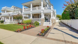 A two-story house with a balcony, a stone chimney, and a well-maintained garden with colorful flowers. - Spacious Avalon Beach House - 2 Blocks to Water! (Avalon)