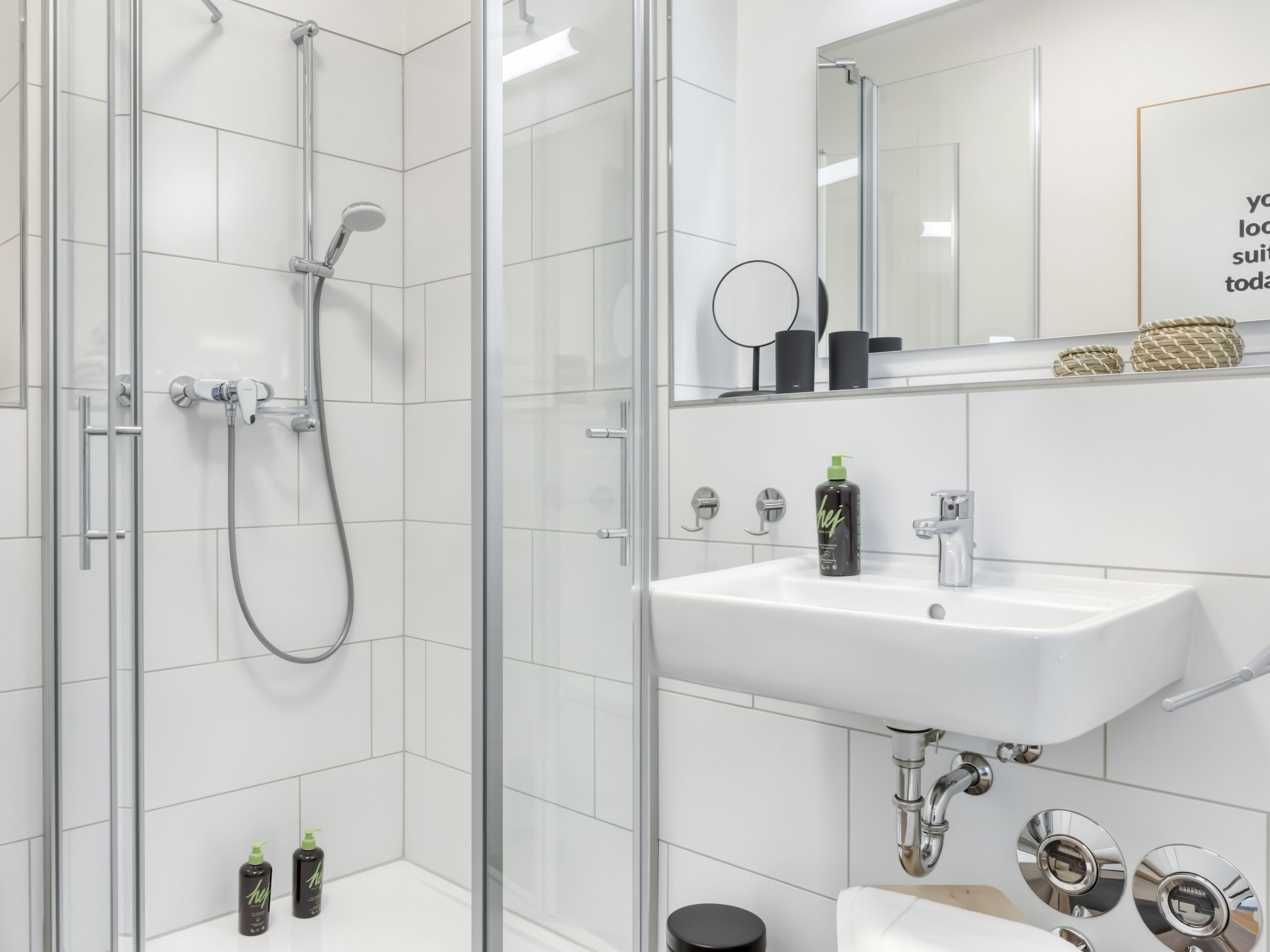 A modern bathroom with a glass-enclosed shower, a white sink, and a mirror above the sink.