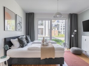 Un dormitorio moderno con una cama grande, una mesita de noche, una lámpara, un ventilador y un televisor.