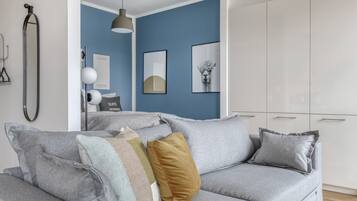 Een moderne woonkamer met een grijze bank, een witte garderobe en een blauwe accentmuur.