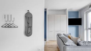 A modern living room with a grey sofa, a mounted TV, and a shower enclosure.