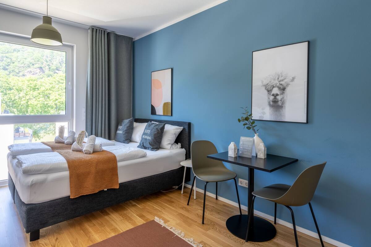 Een moderne slaapkamer met een bed, nachtkastje, stoelen en kunstwerken aan de muur.