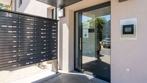 Une entrée moderne avec un portail numéroté, une porte en verre et un écran numérique.