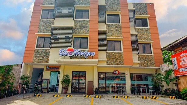Un hôtel à plusieurs étages, appelé Blue Horizon, doté d’une façade moderne, de nombreux balcons et d’un restaurant situé au rez-de-chaussée.