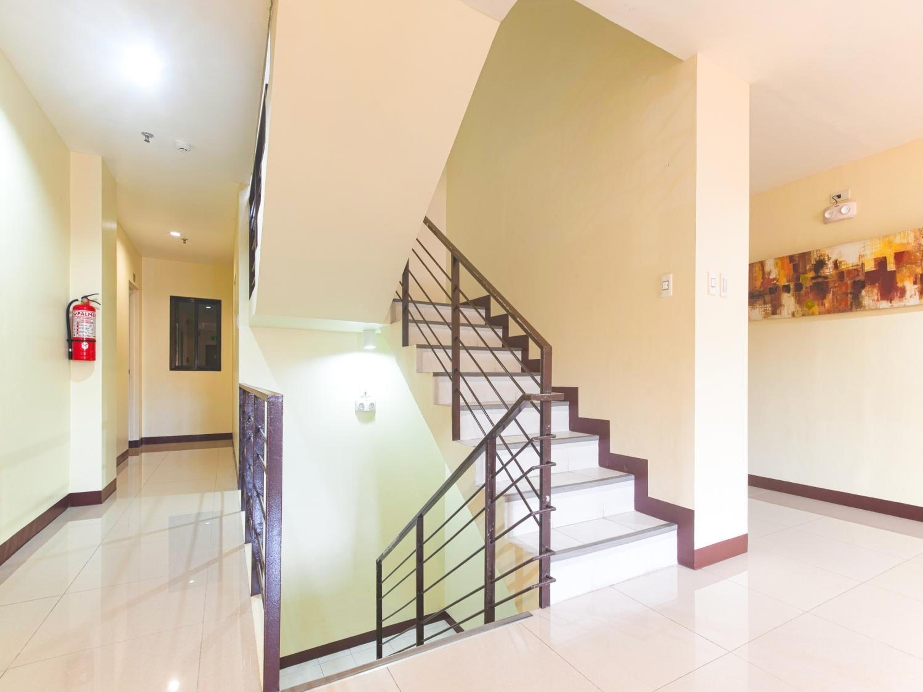 A modern interior with a staircase, a fire extinguisher, and a painting on the wall.