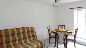 En stue med en farverig sofa, et spisebord med stole og en loftsvifte.