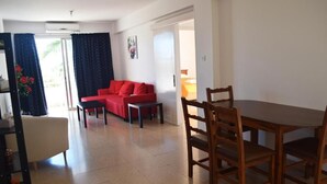 Un comedor con una mesa y sillas de madera, un sofá rojo y una pequeña mesa con una silla.