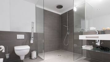 A modern bathroom with a glass shower enclosure, a white toilet, and a vanity with a mirror.