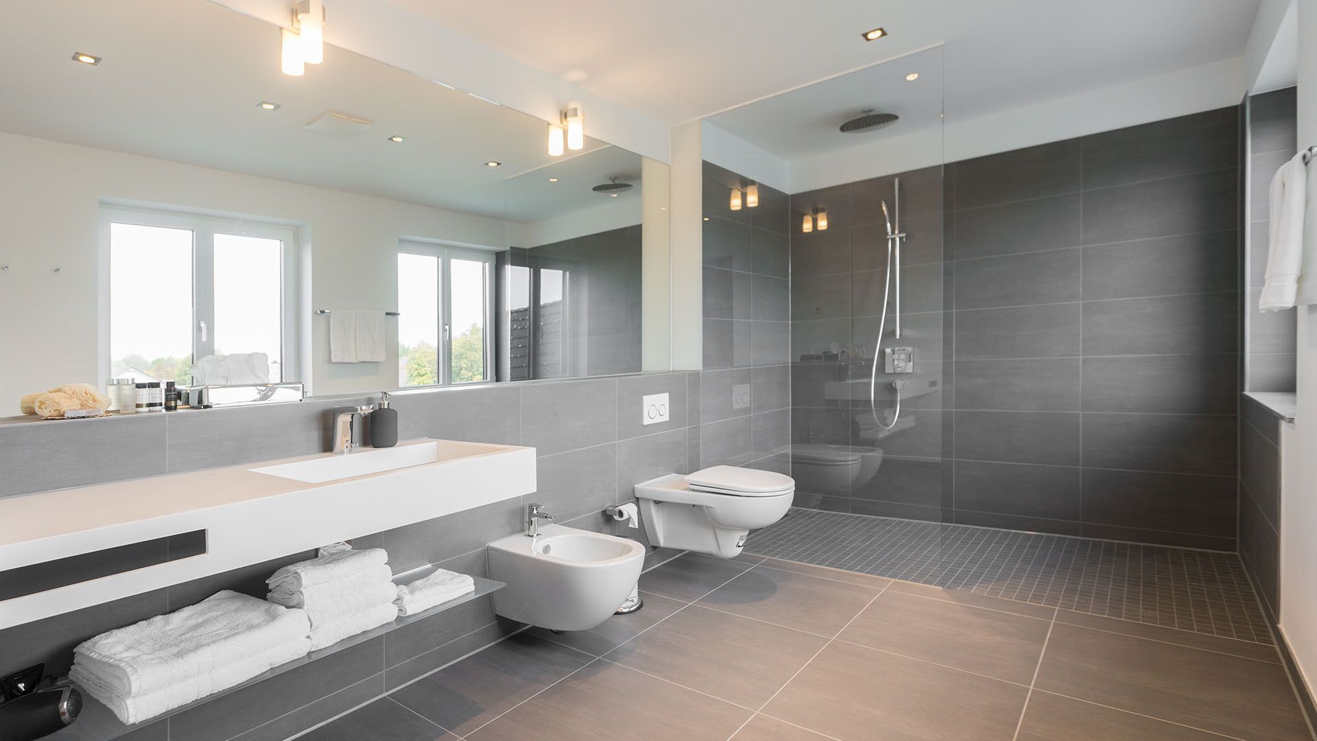Une salle de bain moderne avec un grand miroir, une baignoire, des toilettes et un espace douche.