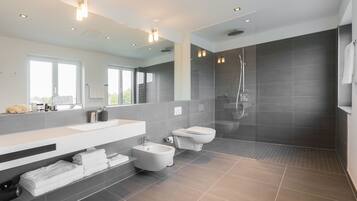 Une salle de bain moderne avec un grand miroir, une baignoire, des toilettes et un espace douche.