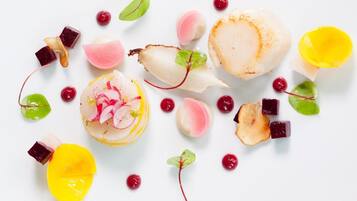 A variety of food items including scallops, radishes, and possibly mango slices, arranged on a white surface.