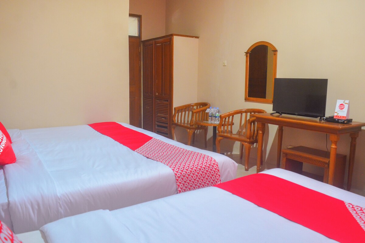 A hotel room with two beds, a desk with a television, and a mirror on the wall.