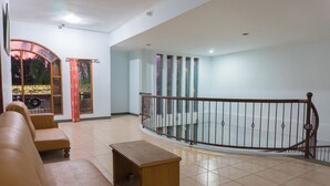 A spacious living area with a wooden bench, a sofa, and a staircase with a metal railing. - Hotel O Pantai Jaya (Pangandaran)