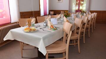 A dining area with a long table set for a meal, surrounded by chairs.