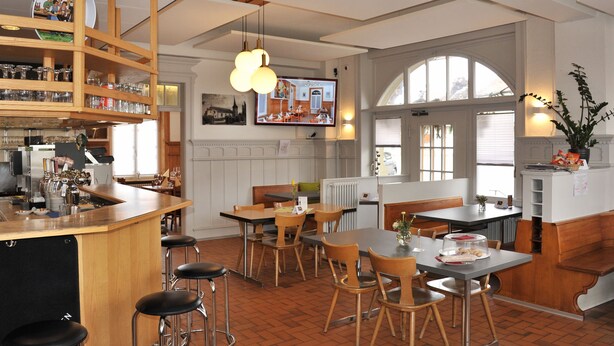 Une cuisine spacieuse dotée d’un bar en bois, de plusieurs coins salon et de grandes fenêtres laissant entrer la lumière naturelle.