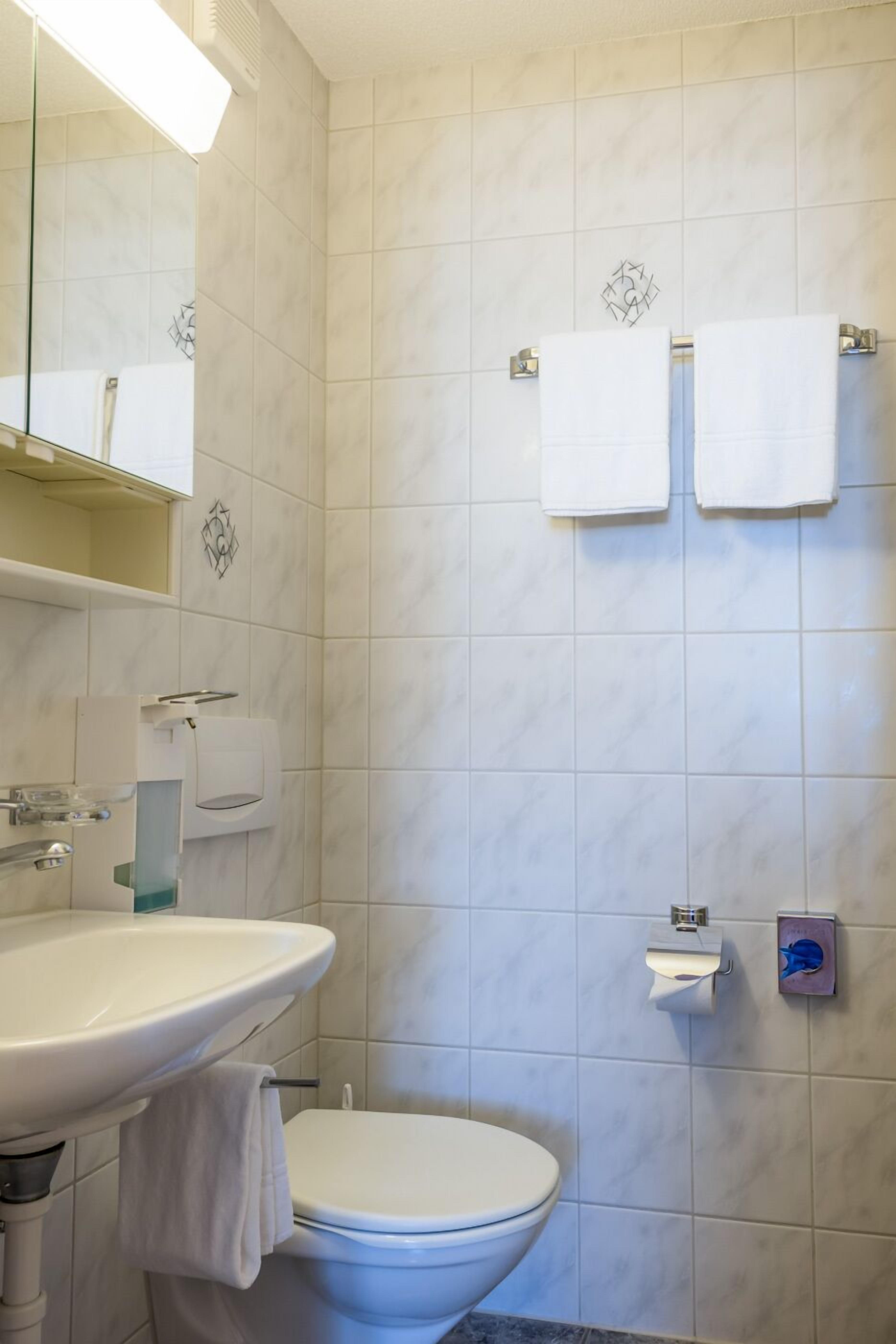 A bathroom with a sink, toilet, and two towels hanging on the wall.