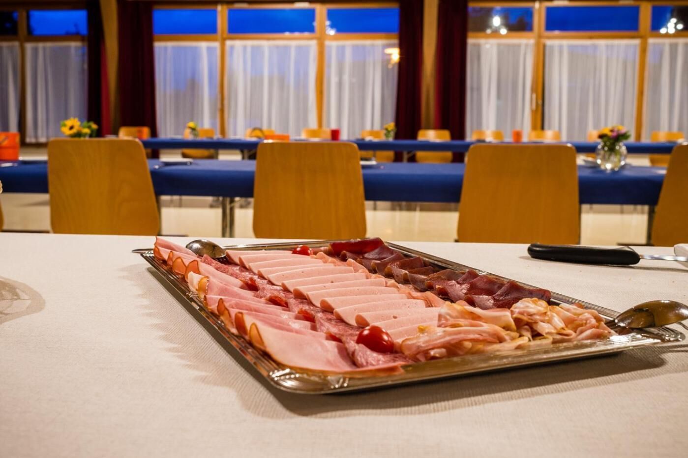A buffet table with various meats arranged in a tray.