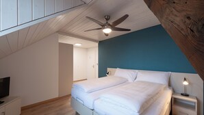 Une chambre à coucher avec un lit, une table de chevet, un téléviseur et un ventilateur de plafond.