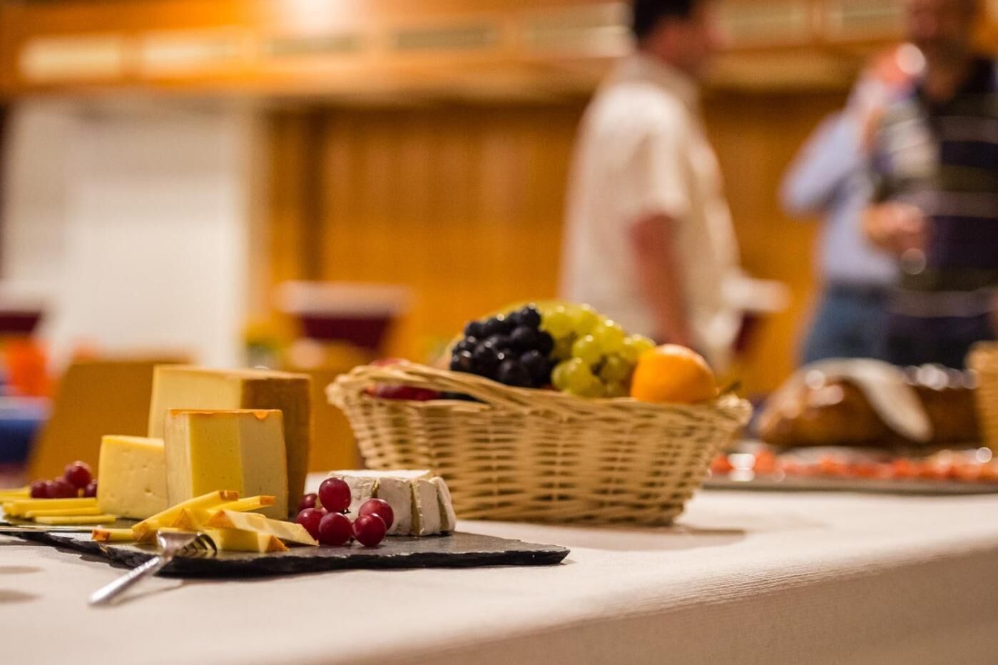 Ein reichhaltiges Buffet mit verschiedenen Käsesorten, Früchten und einem Korbwägelchen.