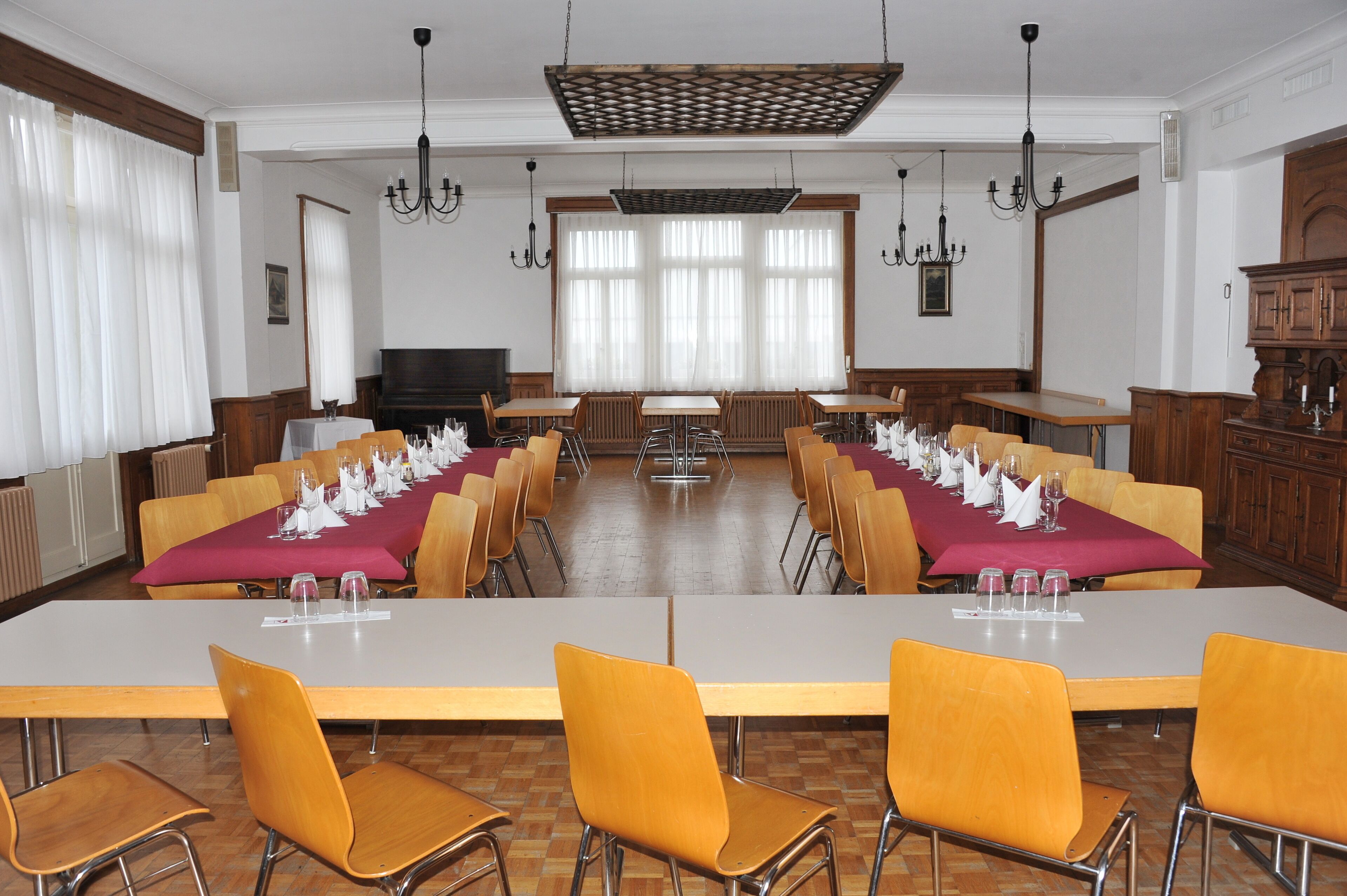 Une salle de conférence équipée de longues tables, de chaises et d’un téléviseur.