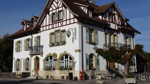 Un bâtiment traditionnel à colombages, doté d’un balcon, de jardinières et d’une enseigne indiquant qu’il s’agit d’un restaurant.