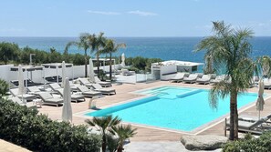 A rooftop pool area with lounge chairs and a view of the ocean. - Midenza Seaside & Nature Retreat (Ricadi)