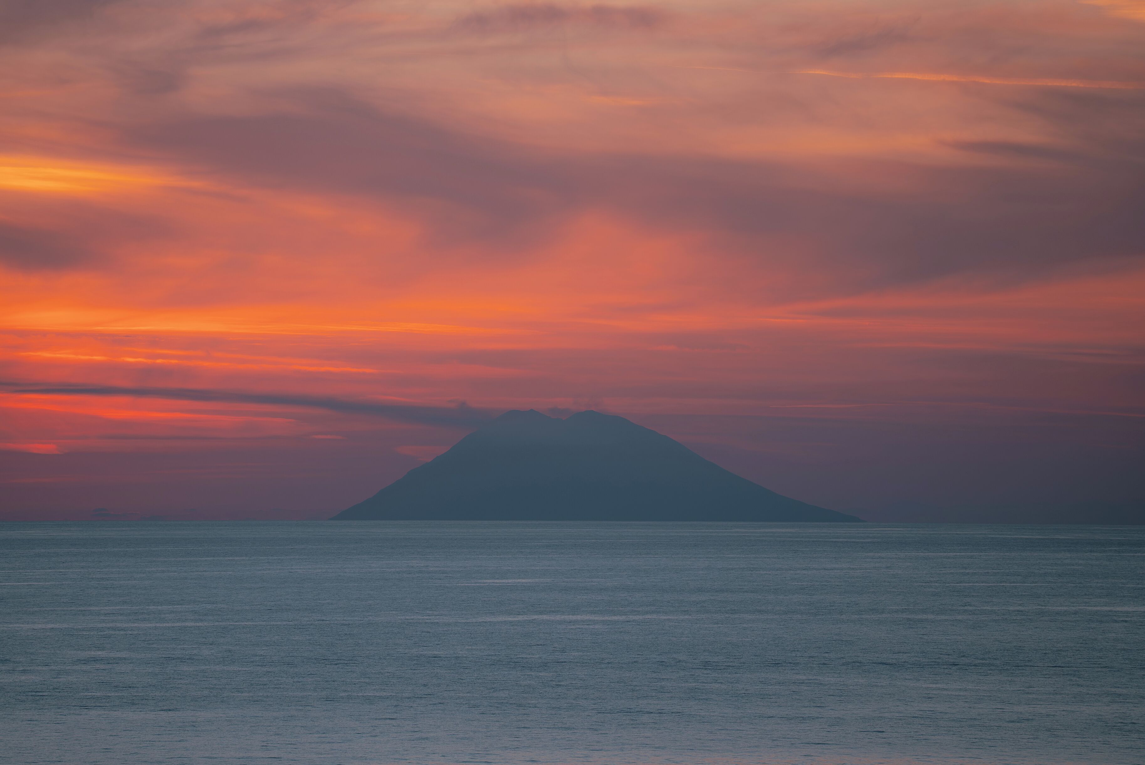 Silueta de montaña contra un cielo al atardecer, vista desde el agua.