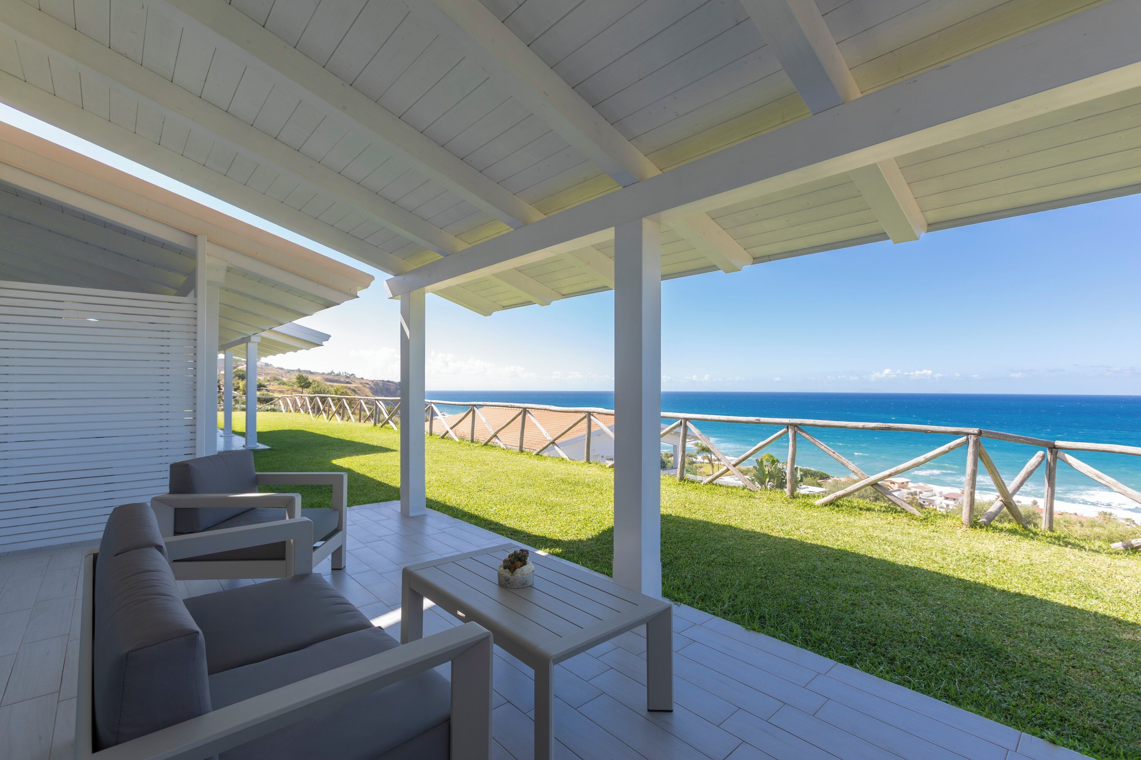 An outdoor patio with a white ceiling and a view of the ocean.