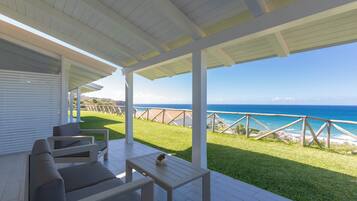 An outdoor patio with a white ceiling and a view of the ocean.