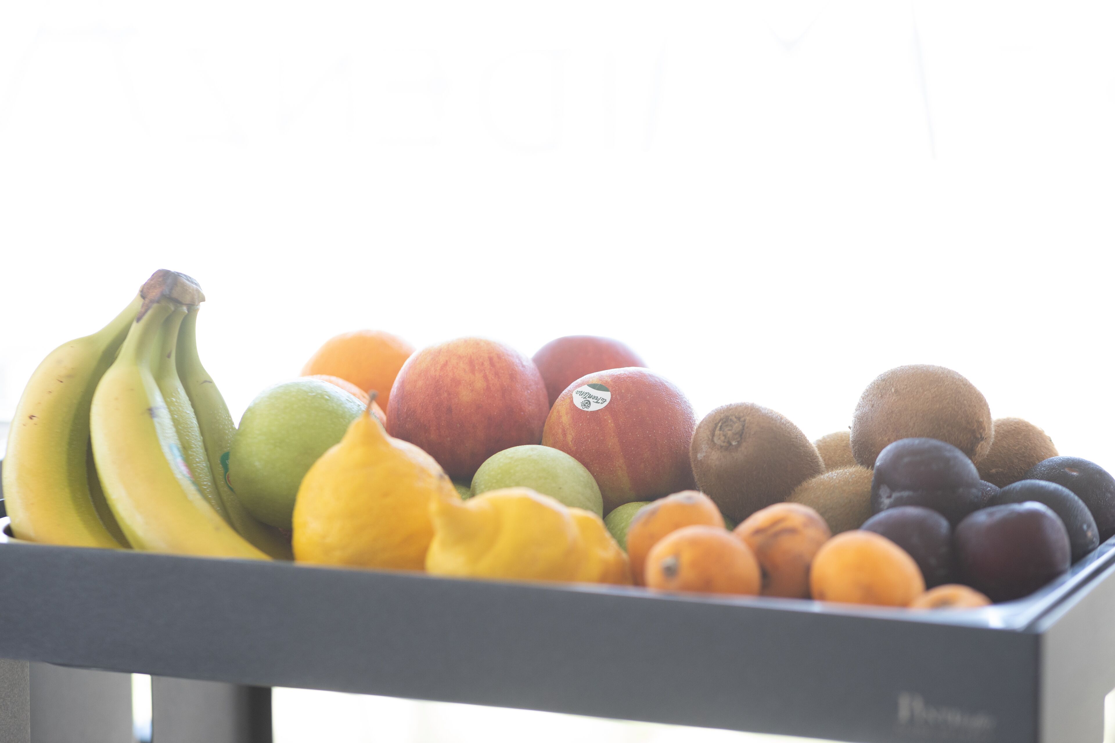Un cuenco con plátanos, manzanas, kiwis, naranjas y peras.