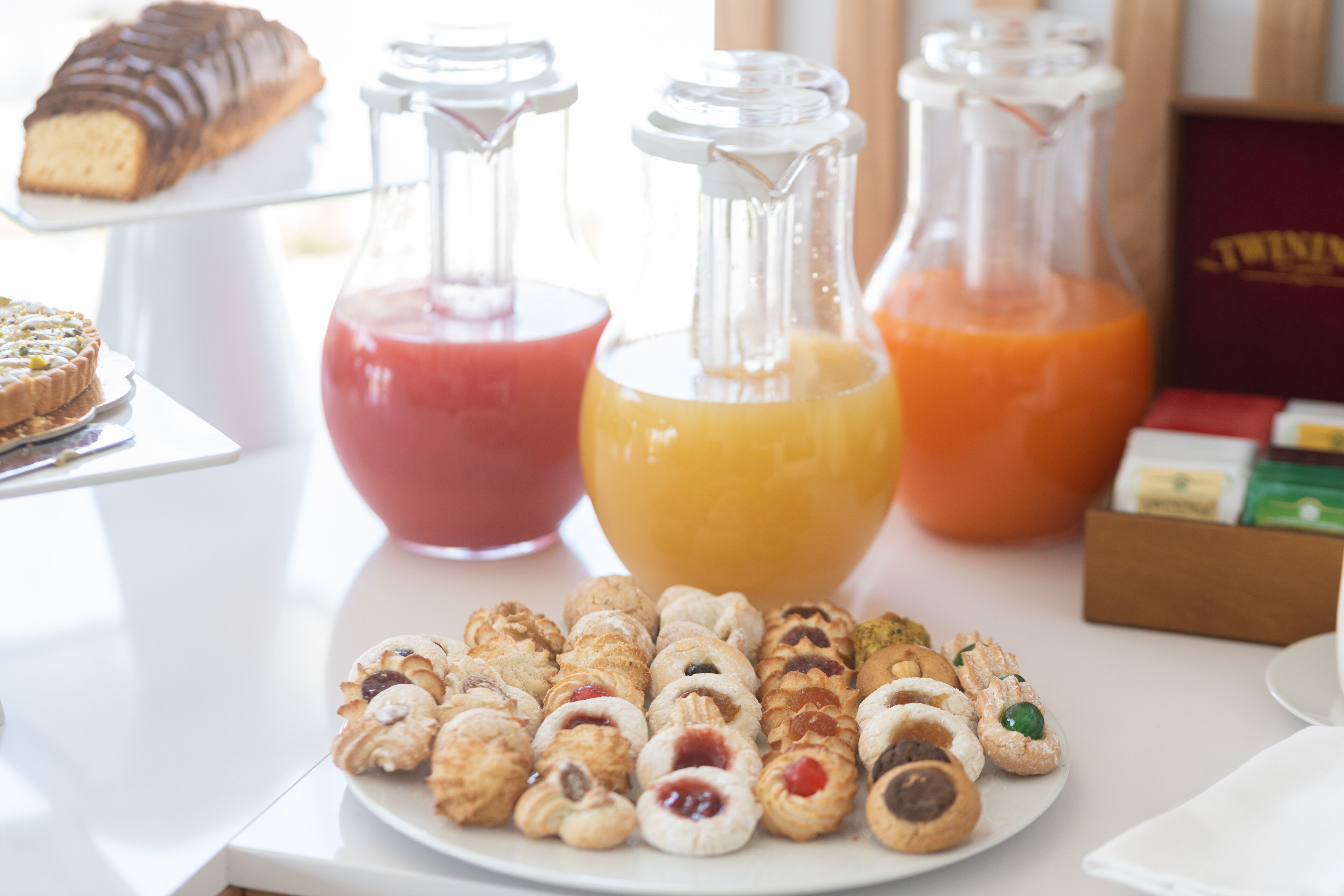 A table with various pastries and two glass bottles containing red and orange liquids.