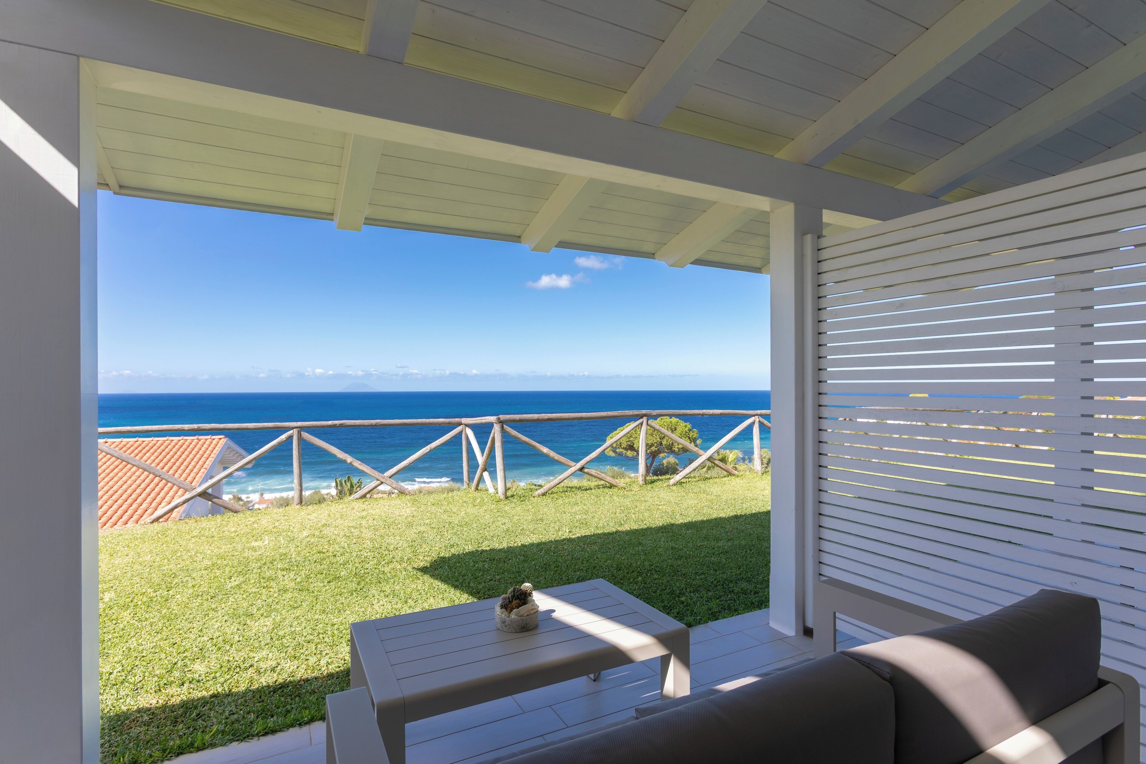 A covered outdoor seating area with a view of the ocean.