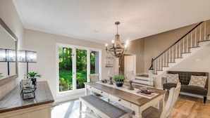 A spacious kitchen with a dining area, a staircase, and a view of the outdoors. - Nights on Normandy (Mooresville)