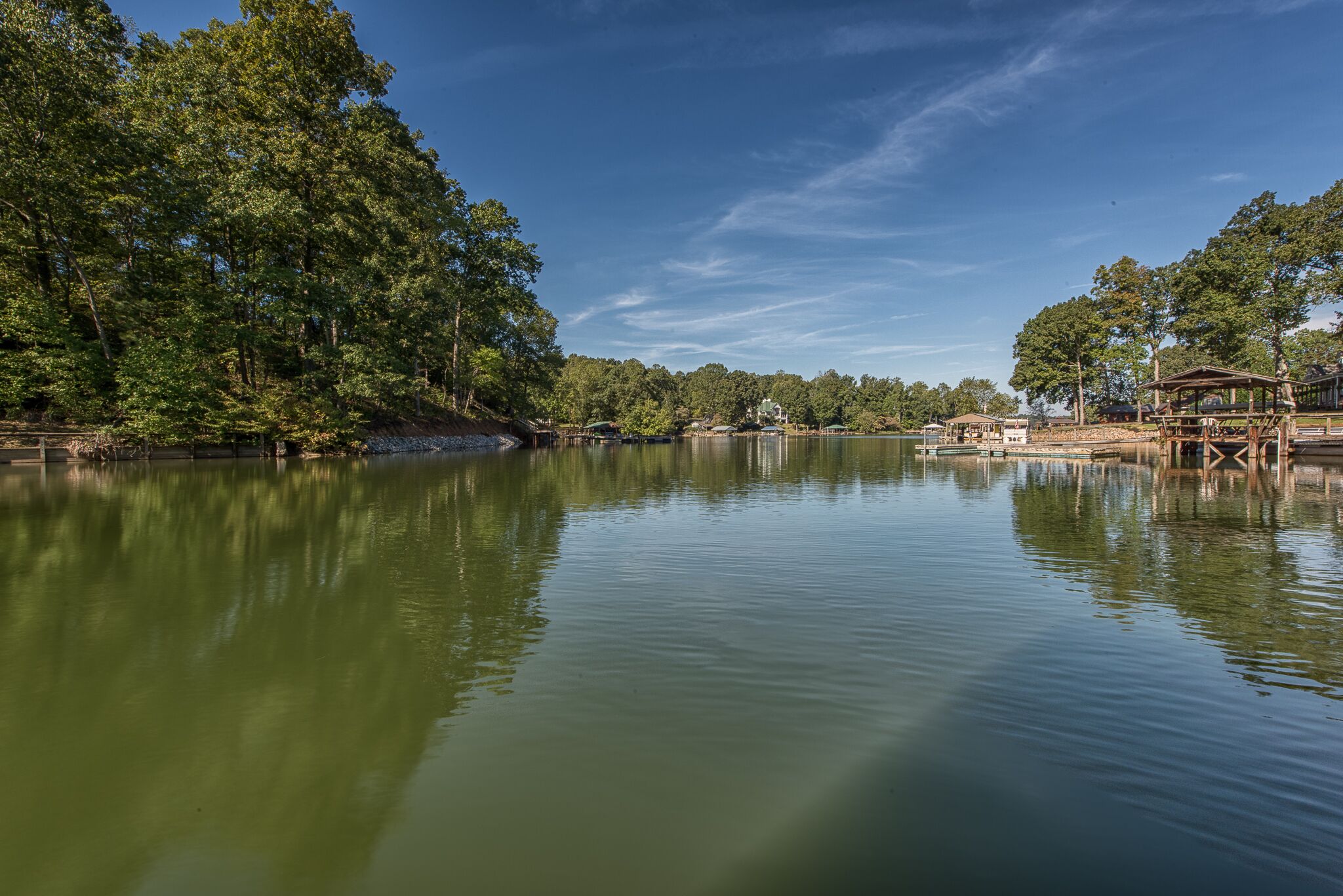 A calm lake surrounded by dense trees and wooden structures.