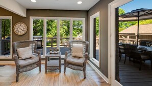 A covered patio with wicker furniture, a grill, and a dining area. - Nights on Normandy (Mooresville)