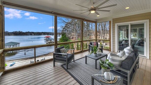 A covered deck with a view of a lake, outdoor furniture, and a ceiling fan. - Bridlewood Cove (Mooresville)