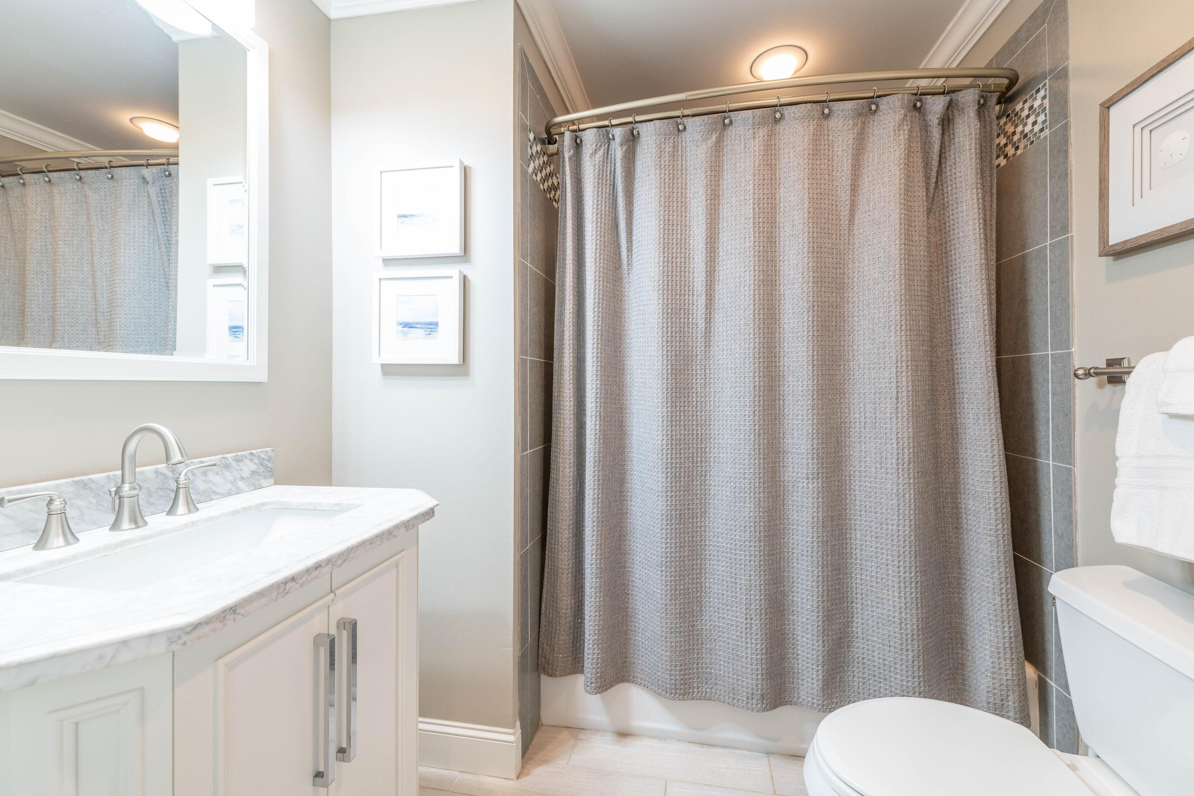 A bathroom with a white sink, a toilet, and a shower curtain.
