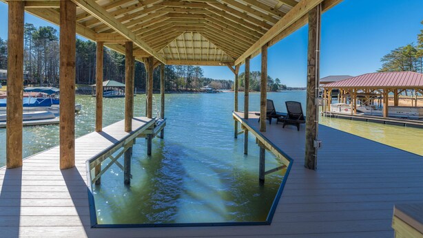 Eine Holzsteg mit Pool mit Glasboden, Holzstühlen und einem überdachten Bereich mit rotem Dach.