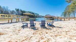 Ein Strand mit zwei Pavillons, einer Holzsteganlage und Liegestühlen.