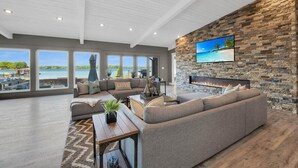 A spacious living room with a large gray sectional sofa, a wooden coffee table, and a stone accent wall with a fireplace. - Lake Norman Breakaway (Mooresville)