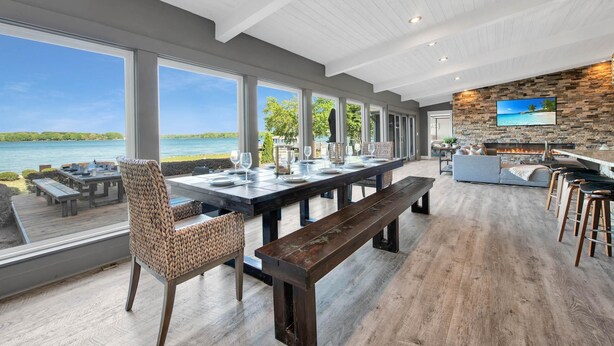 A spacious dining area with a long table, benches, and chairs, overlooking a scenic lake view. - Lake Norman Breakaway (Mooresville)