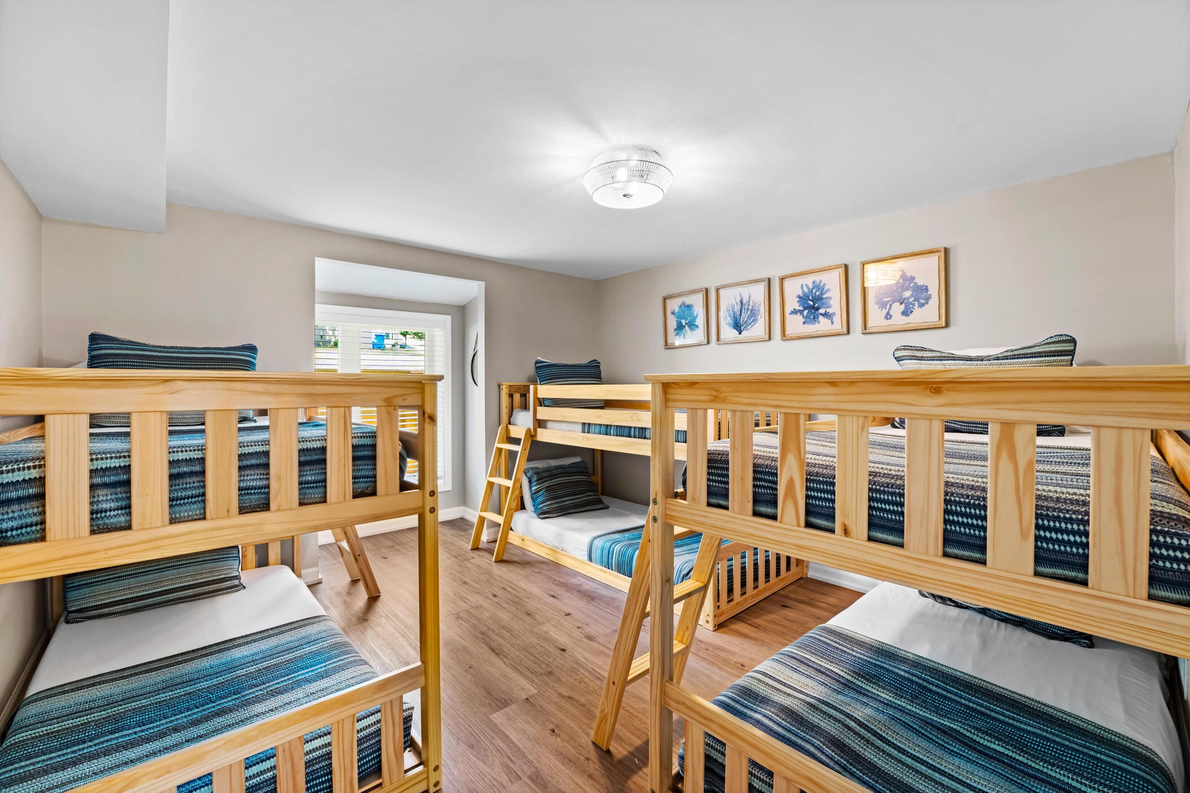 A room with bunk beds, a ladder, and framed artwork on the wall.