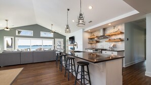 Une cuisine moderne dotée d’un grand îlot central, de tabourets de bar et offrant une vue sur l’eau.