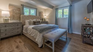 A bedroom with a large bed, two bedside tables, a bench, and a TV on the wall. - No Wake Zone (Mooresville)