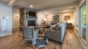 A cozy living room with a stone fireplace, a comfortable sofa, and a dining area. - No Wake Zone (Mooresville)