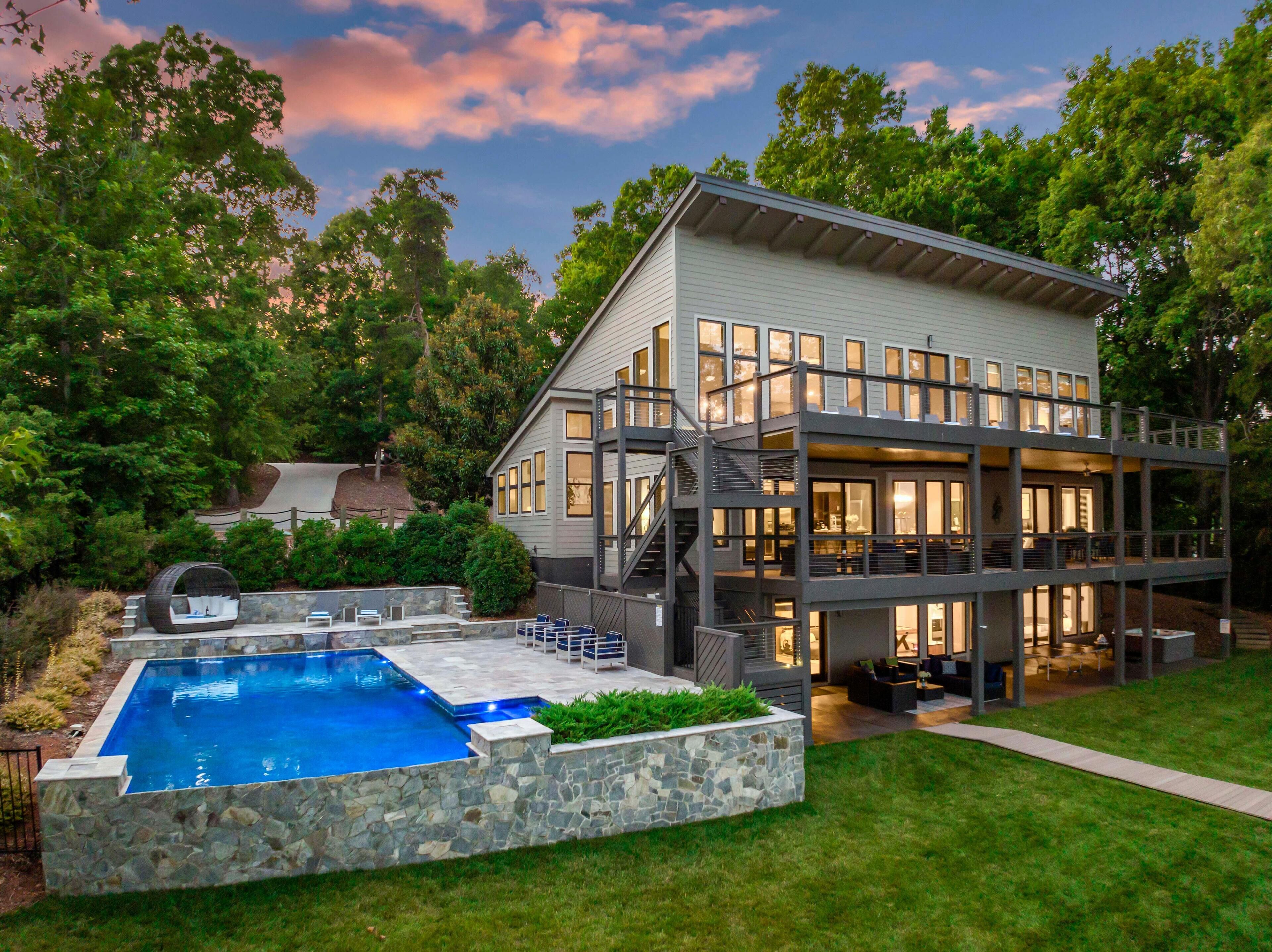 A modern two-story house with a large pool, outdoor seating, and a barbecue area.
