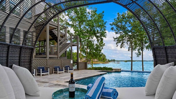 Un área de descanso junto a la piscina con vista al agua, una botella de vino y toallas.