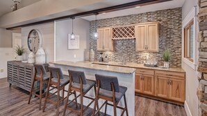 Una cocina moderna con salpicadero de piedra, armarios de madera y una isla central con taburetes de bar.