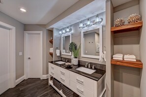 A modern bathroom with two sinks, a large mirror, and built-in shelves. - Sandy Shore (Mooresville)